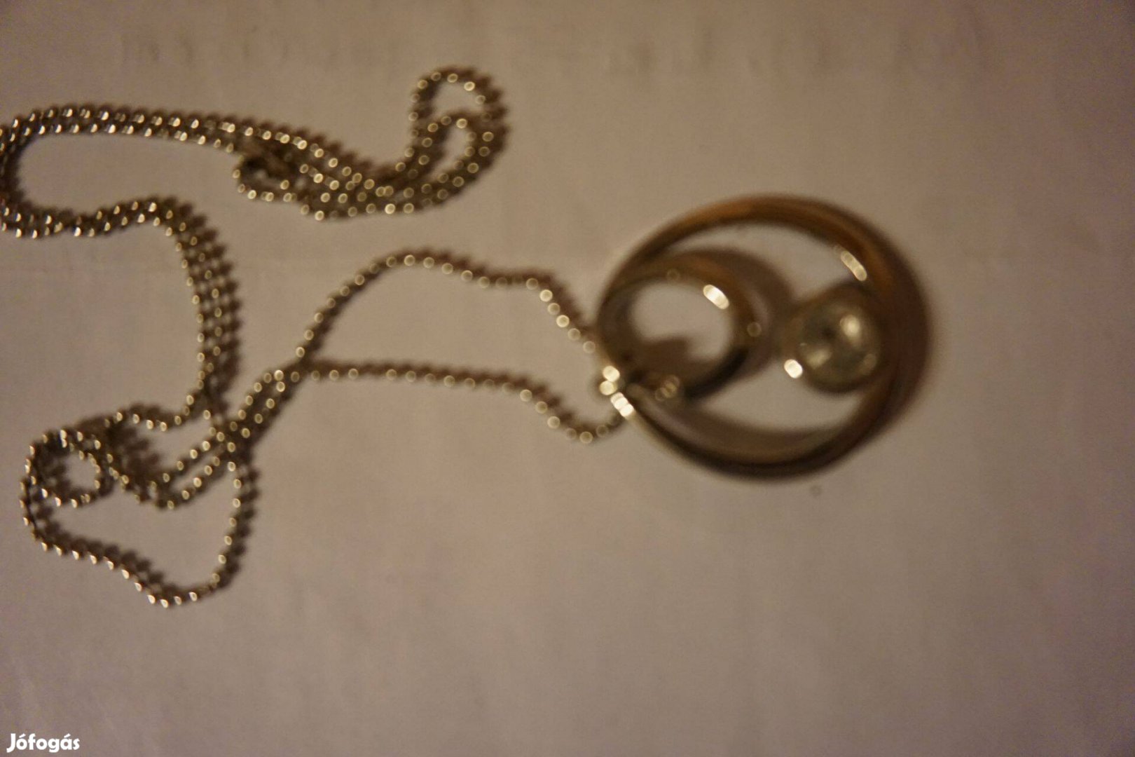 Nyaklánc aranysárga fém medállal, kis csiszolt kvarckővel