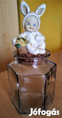 Üveg tároló tetején egy nyuszioverálos babyfigura